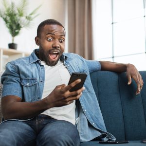 African man reading good news on mobile at home