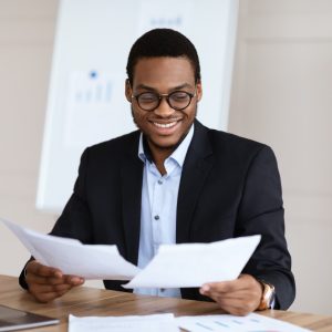 Cheerful young black manager reading marketing report
