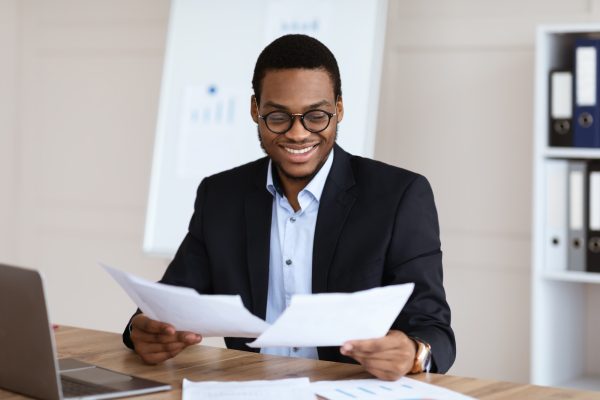 Cheerful young black manager reading marketing report